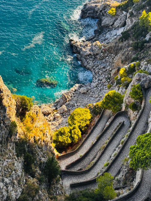 Stunning aerial view of a winding cliffside path above the turquoise sea in Capri, Italy.