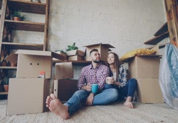 Happy couple sitting among moving boxes, embracing their new home adventure.