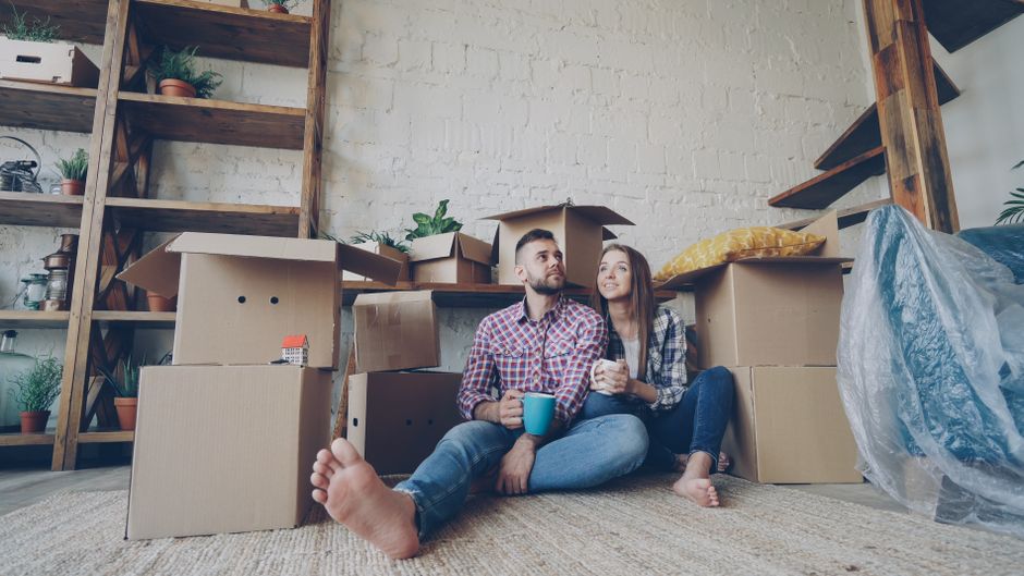 Happy couple sitting among moving boxes, embracing their new home adventure.