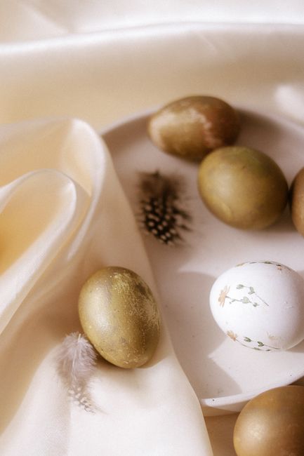Stylish Easter eggs and feathers on satin, perfect for a classy holiday theme.