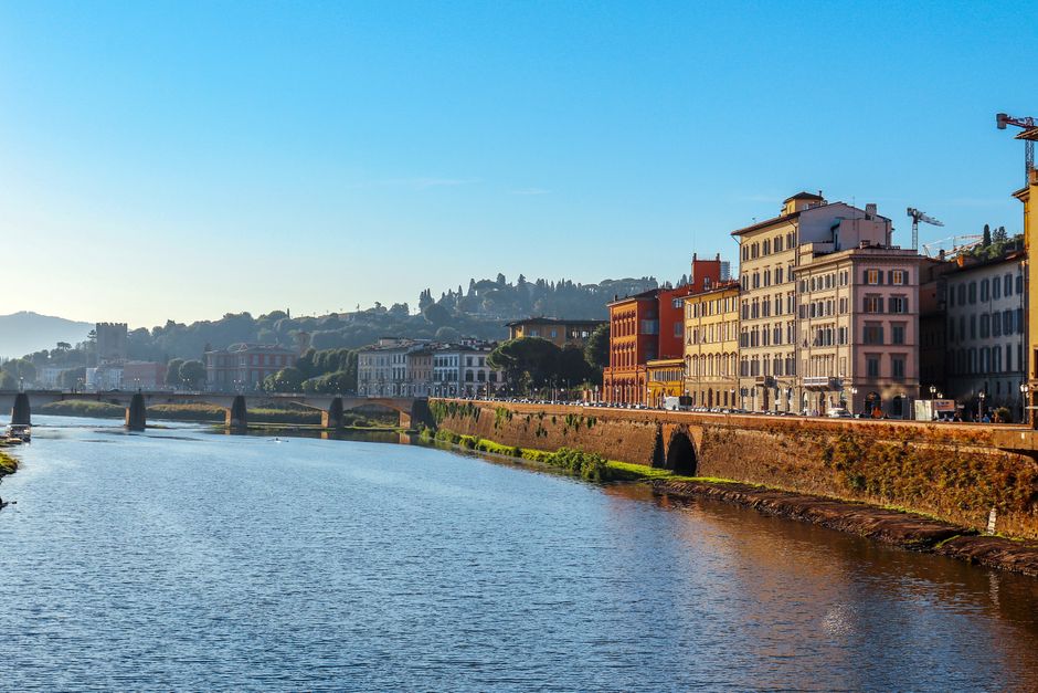 Scenic daytime view of the Arno River with historic buildings in Florence, Italy.