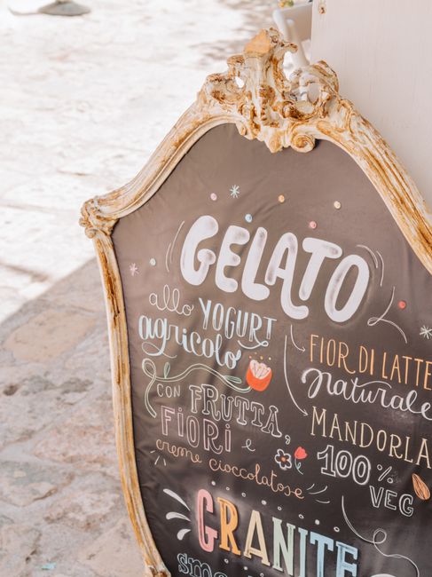 Vintage gelato sign in Polignano a Mare, highlighting flavors like yogurt and fruit, in a rustic setting.