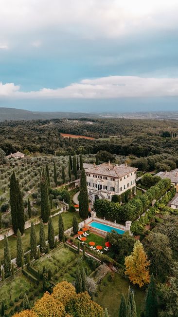 A stunning aerial view of a Tuscan villa surrounded by lush gardens and cypress trees.