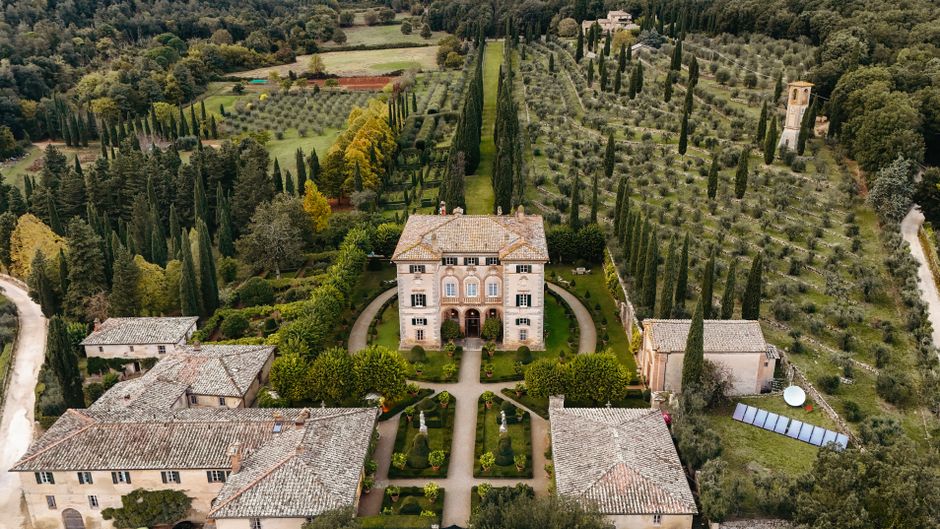 Explore the beauty of Tuscany with this aerial view of a villa surrounded by lush olive groves.