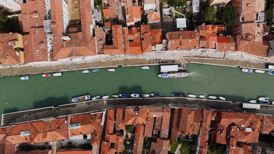 Stunning aerial view of a Venetian canal surrounded by historic red-tiled rooftops and small boats.