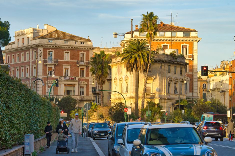 Bustling traffic and pedestrians in central Rome with historic architecture.